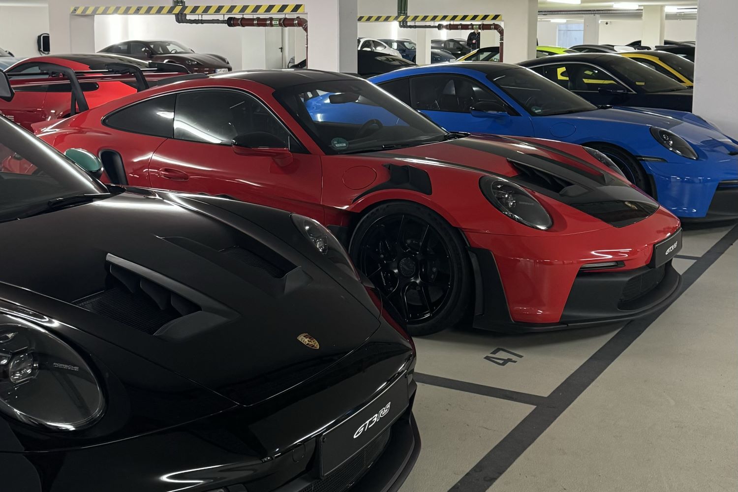 Garage voll mit Porsche Modellen in schwarz, rot und blau.