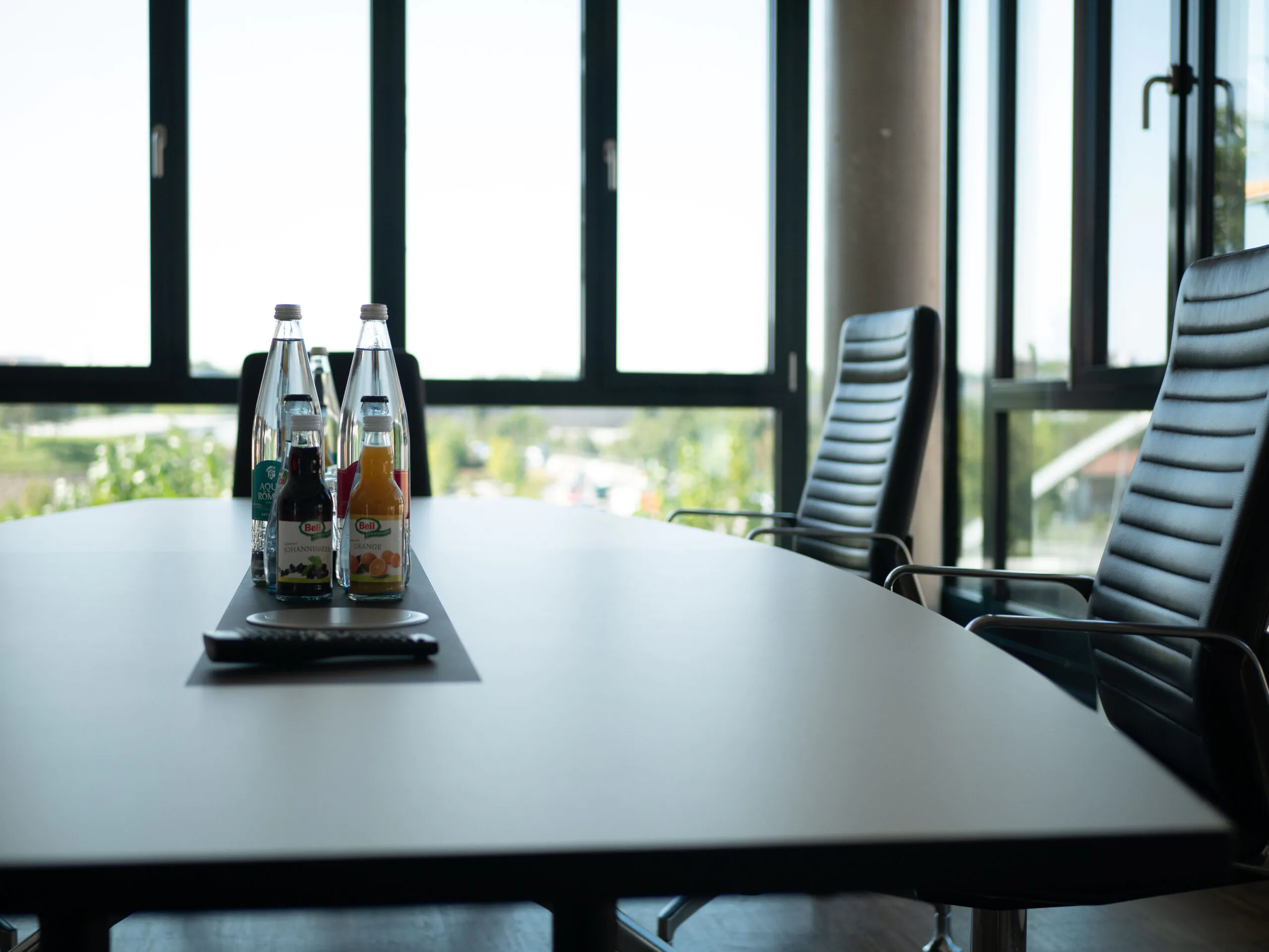 Detailaufnahme von Konferenztisch mit Getränken und Stühlen vor Fensterfront