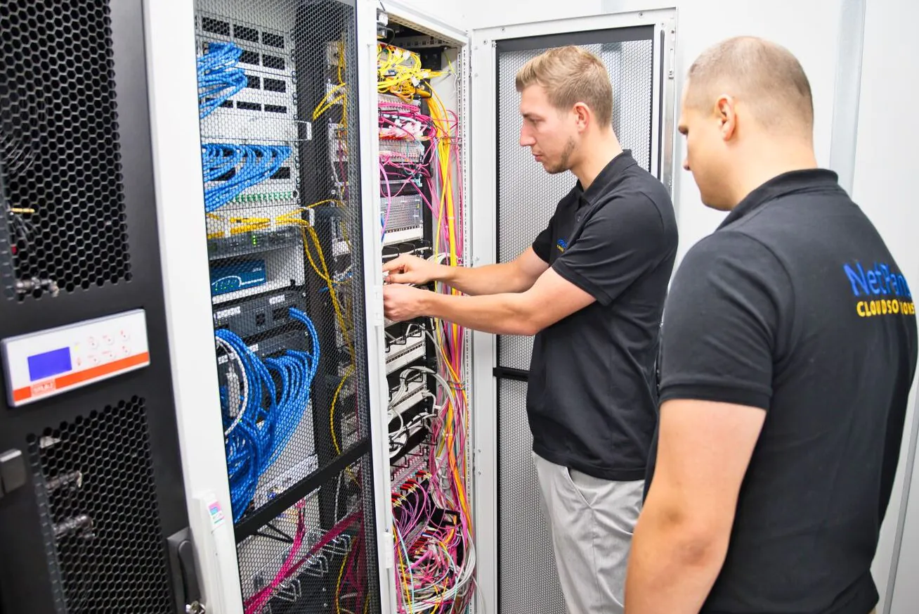 zwei Techniker im Poloshirt installieren Kabel am Serverschrank
